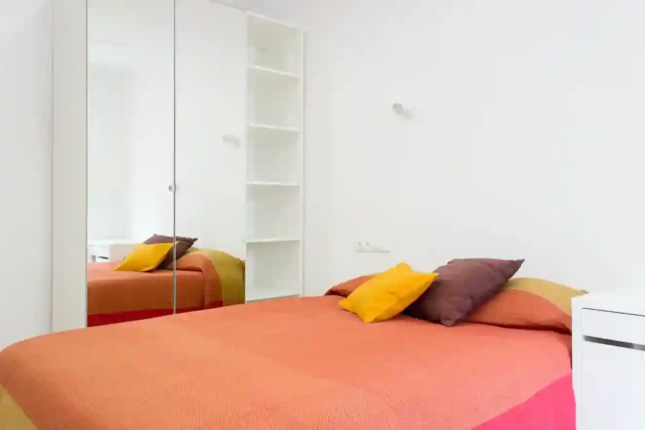 Habitación Espanya en Coliving Vibes Badal con cama doble, escritorio y armario con puertas de espejo