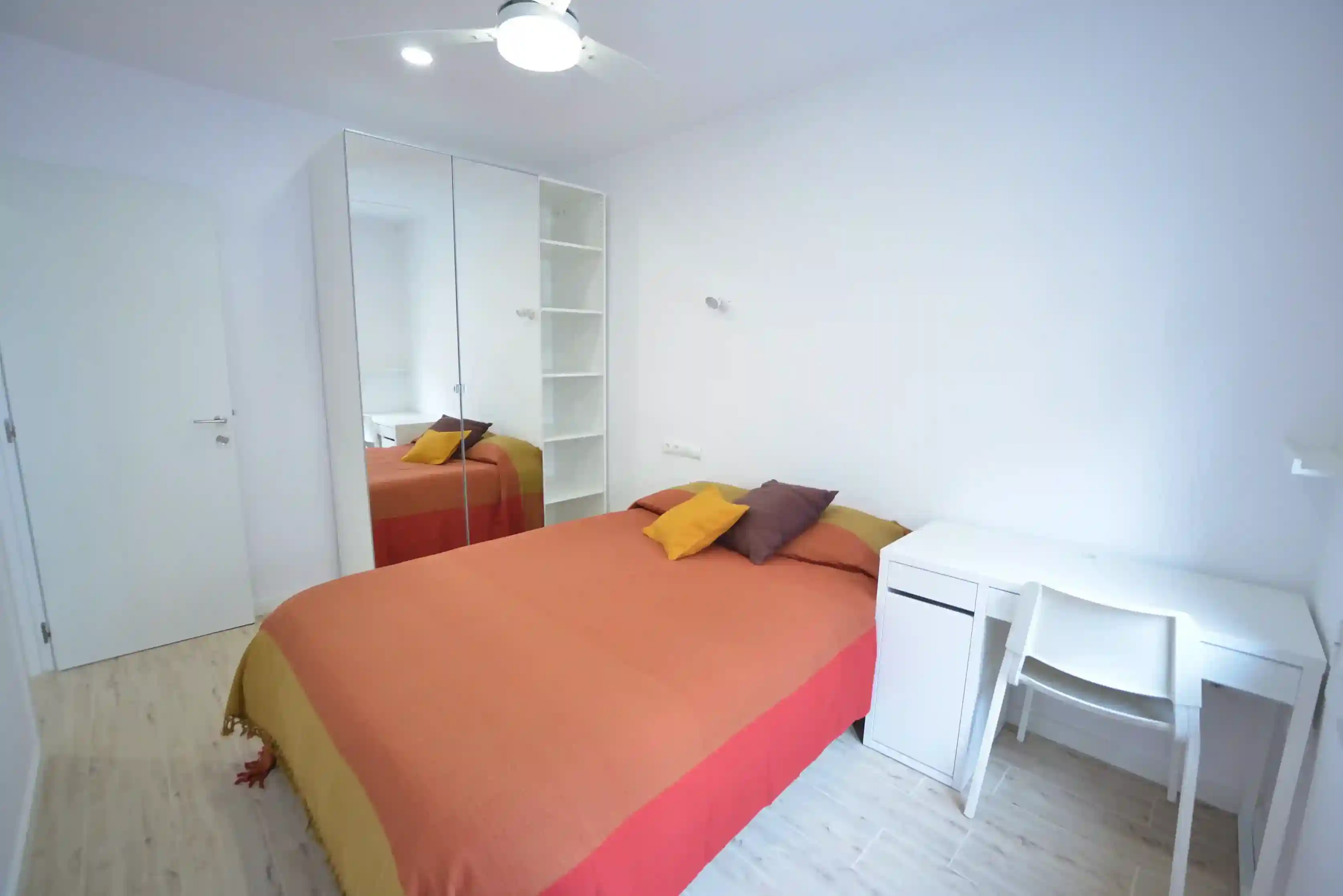 Habitación Espanya en Coliving Vibes Badal con cama doble, escritorio y armario con puertas de espejo