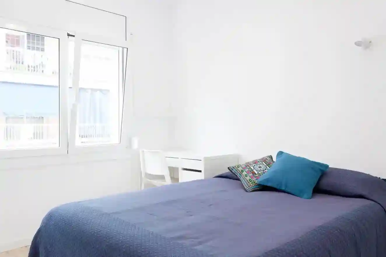 Habitación individual luminosa con escritorio junto a la ventana y cama doble en Coliving Vibes Badal